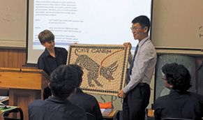 A Latin teacher holding a tapestry with a dragon on it
